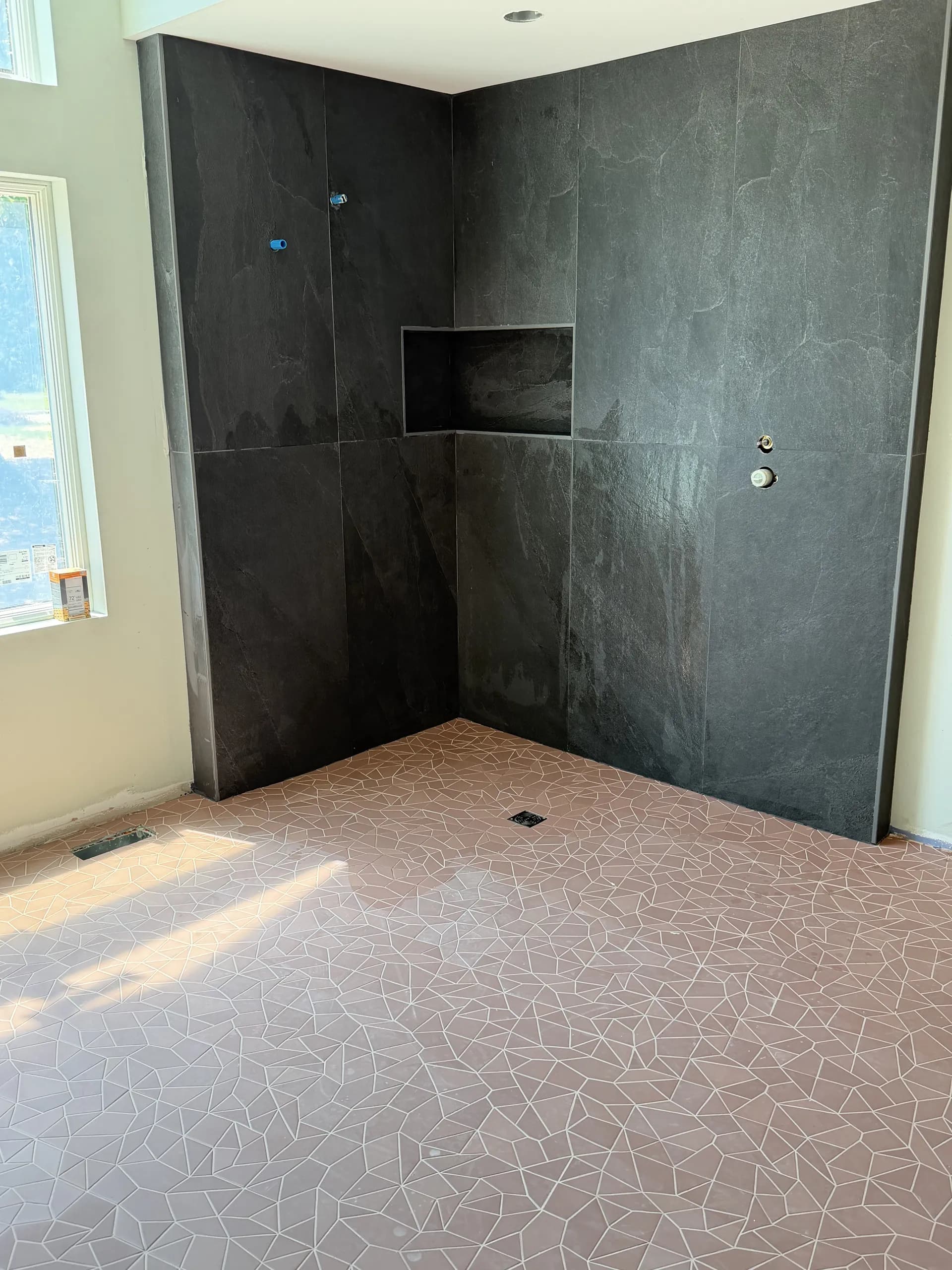 Bathroom remodel with walk-in shower, charcoal wall tile, and geometric floor tile