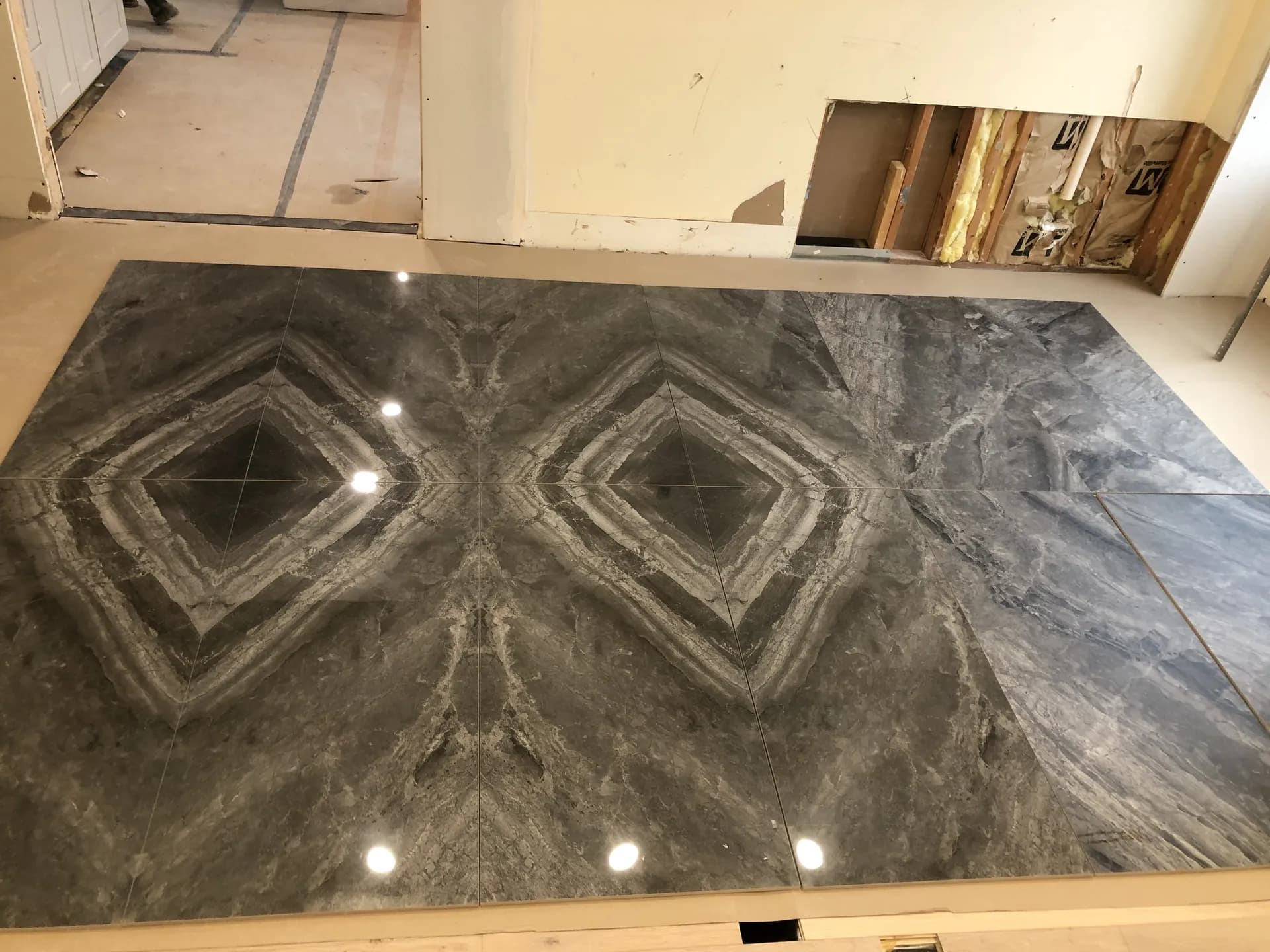 Large-format porcelain floor tile installed in a bookmatched pattern during a residential remodel
