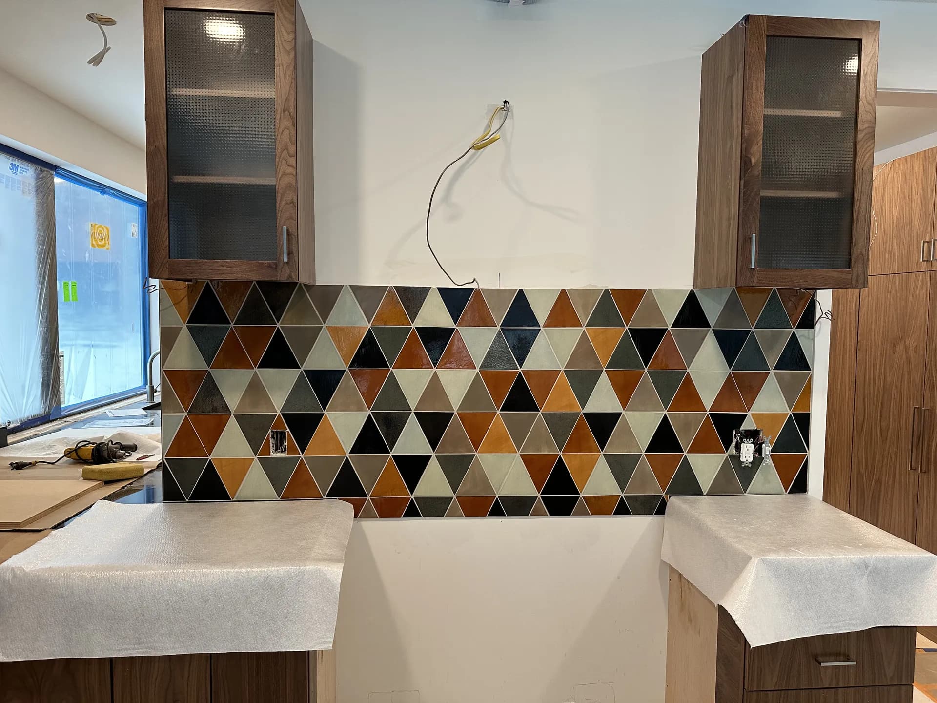 Colorful geometric triangular mosaic backsplash installed in a kitchen remodel